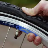 Daumen prüft den Fahrradreifen. Wie viel bar braucht der Reifen? Die Felge zeigt "X-PLORER".