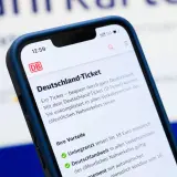 Smartphone zeigt Details zum Deutschland-Ticket. Die Kosten für 2026 sind noch nicht bekannt, aber das Ticket bietet unbegrenzte Fahrten.