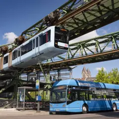 Die Schwebebahn Wuppertal fährt über einem blauen Bus. Mit dem Deutschlandticket ist das ganze Tal mobil.