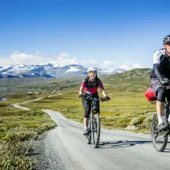 Zwei Radfahrer genießen eine atemberaubende Radtour in Schweden. Berge und ein See bilden die Kulisse für ihr Abenteuer.