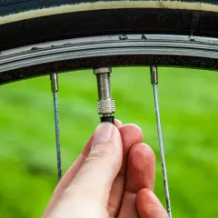 Hand schraubt am Fahrradventil. Ein kleines Teil am Ventil wird gerade befestigt, um das Fahrradventil wechseln zu können.