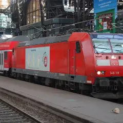 Rote Lokomotive der Baureihe 146 mit Doppelstockwagen im Bahnhof.