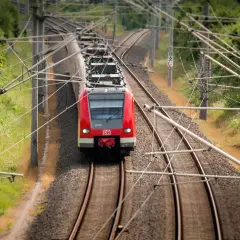 Rote DB-Bahn fährt auf Gleisen. Hier kann man alte Fahrscheine umtauschen, wenn man die Reise neu plant.