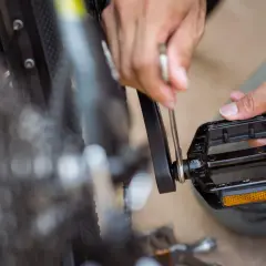 Hände reparieren ein Fahrrad. Ein Werkzeug wird angesetzt, um die Fahrrad Pedale knacken zu beheben.