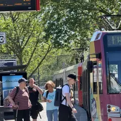 Menschen warten an Gleis 3 auf die Bahn. Die Anzeige zeigt "1 Weiden", was die einfache Fahrt Bedeutung für die Reisenden verdeutlicht.