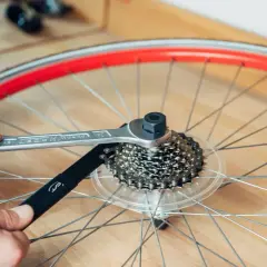Werkzeug löst die Kassette am Fahrrad. Hände halten Werkzeug und Kettenpeitsche, um die Kassette zu wechseln.