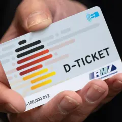 Ein Finger hält das Deutschlandticket. Mit diesem Ticket kann man bequem mit dem ICE und anderen Zügen durch Deutschland reisen.