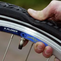 Daumen prüft den Fahrradreifen. Wie viel bar braucht der Reifen? Die Felge zeigt "X-PLORER".