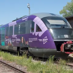 Der Triebzug br 642 mit der Nummer 642147 steht auf Gleisen, die Seiten sind lila und türkis bemalt.