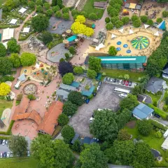 Luftaufnahme eines Freizeitparks mit bunten Spielplätzen, Trampolinen und viel Grün. Hier toben die nrw kids ausgelassen.
