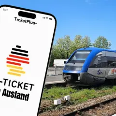 Smartphone-App zeigt "D-TICKET im Ausland" mit Deutschlandflagge. Im Hintergrund ein blauer Zug am Bahnsteig.