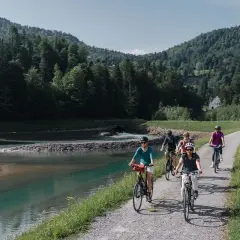 Eine Gruppe radelt entlang eines Flusses in den Bergen. Die komoot Fahrrad App hat sie sicher hierher geführt.