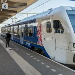 Eine Frau wartet auf dem Bahnsteig auf den Zug. Der blaue Arriva-Zug mit dem roten Löwenwappen ist ein Teil des Nahverkehrs in den Niederlanden.