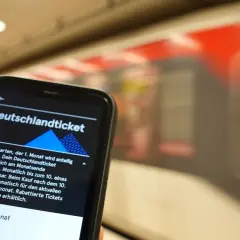 Smartphone zeigt Deutschlandticket-App. Die Frage "wann wird das Deutschlandticket abgebucht" wird beantwortet: Automatisch am Monatsende, kündbar bis zum 10.