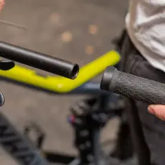 Person wechselt Lenkergriffe am Fahrrad. Ein neuer Griff wird auf den Lenker geschoben.