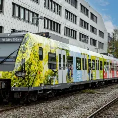 Der br 423 Zug feiert 50 Jahre S-Bahn München mit einer bunten Folierung, die Naturmotive und Jubiläumslogos zeigt.