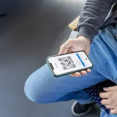 Person zeigt Smartphone mit QR-Code für Deutschlandticket-Kontrolle.