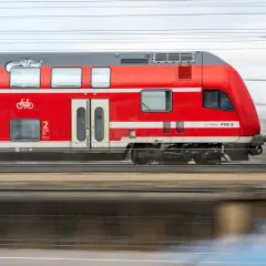 Roter Doppelstockzug der Deutschen Bahn fährt schnell. Ein Fahrradsymbol weist auf Fahrradmitnahme hin. Ideal für den Nahverkehr.