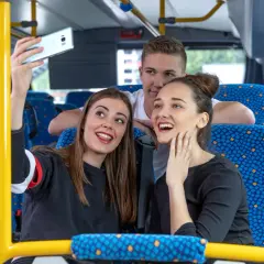 Drei junge Leute machen ein Selfie im Bus. Vielleicht sind sie auf dem Weg zu einem Konzert und hoffen, dass das Transdev Deutschlandticket keine Probleme macht.