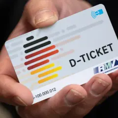 Hand hält ein D-Ticket mit Deutschlandfarben. Hoffentlich wurde das Deutschlandticket nicht doppelt gebucht!