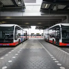 Zwei moderne Stadtbusse stehen unter einem Vordach. Man fragt sich, wie viel PS ein Bus hat, um diese Giganten zu bewegen.