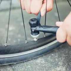 Hände pumpen mit einer Handpumpe Luft in ein Fahrradventil.
