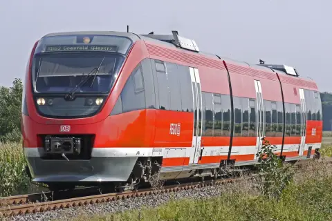 Roter Regionalexpress der DB fährt durch Kornfelder. Mit dem Deutschlandticket ist diese Fahrt ein Vergnügen.