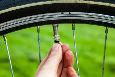 Hand schraubt am Fahrradventil. Ein kleines Teil am Ventil wird gerade befestigt, um das Fahrradventil wechseln zu können.