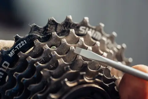 Nahaufnahme einer Fahrradkassette. Ein Schraubendreher berührt die Zähne. Mögliche Symptome einer zu langen Fahrradkette sind schleifende Gänge.