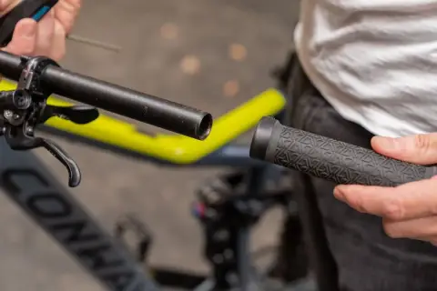 Person wechselt Lenkergriffe am Fahrrad. Ein neuer Griff wird auf den Lenker geschoben.