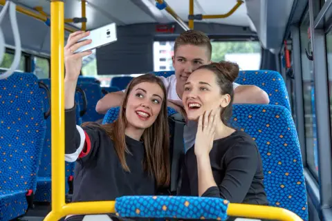 Drei junge Leute machen ein Selfie im Bus. Vielleicht sind sie auf dem Weg zu einem Konzert und hoffen, dass das Transdev Deutschlandticket keine Probleme macht.