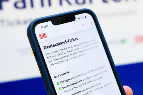 Smartphone zeigt Details zum Deutschland-Ticket. Die Kosten für 2026 sind noch nicht bekannt, aber das Ticket bietet unbegrenzte Fahrten.