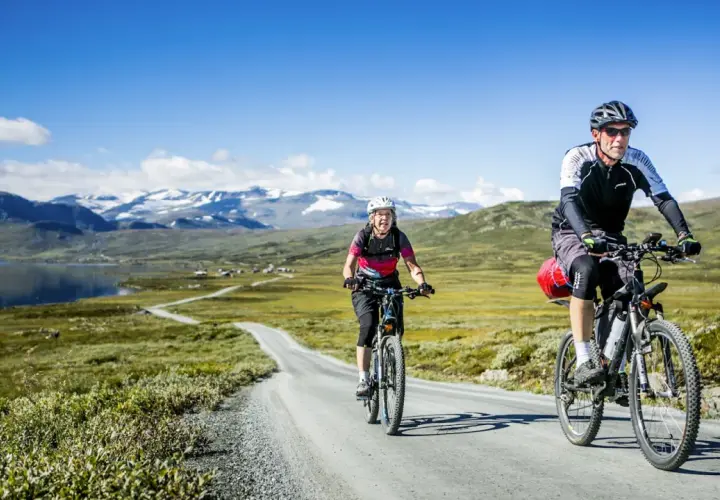 Zwei Radfahrer genießen eine atemberaubende Radtour in Schweden. Berge und ein See bilden die Kulisse für ihr Abenteuer.