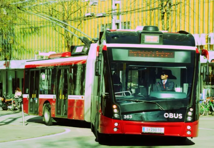 Ein roter Obus mit der Nummer 363 fährt auf der Straße. Der Fahrer trägt eine Sonnenbrille und eine Uniform.