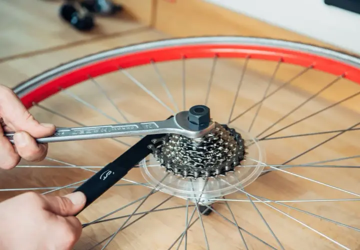 Werkzeug löst die Kassette am Fahrrad. Hände halten Werkzeug und Kettenpeitsche, um die Kassette zu wechseln.