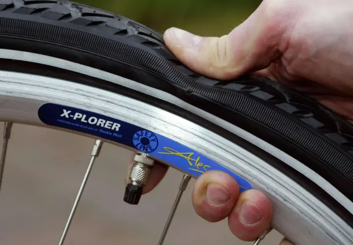 Daumen prüft den Fahrradreifen. Wie viel bar braucht der Reifen? Die Felge zeigt "X-PLORER".