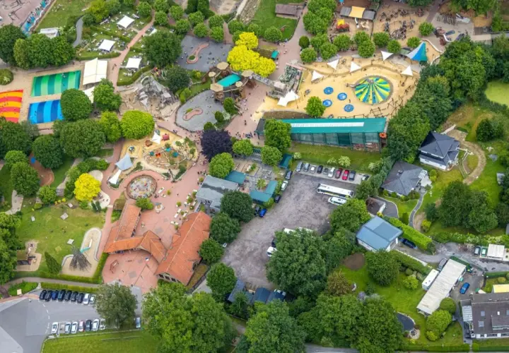 Luftaufnahme eines Freizeitparks mit bunten Spielplätzen, Trampolinen und viel Grün. Hier toben die nrw kids ausgelassen.