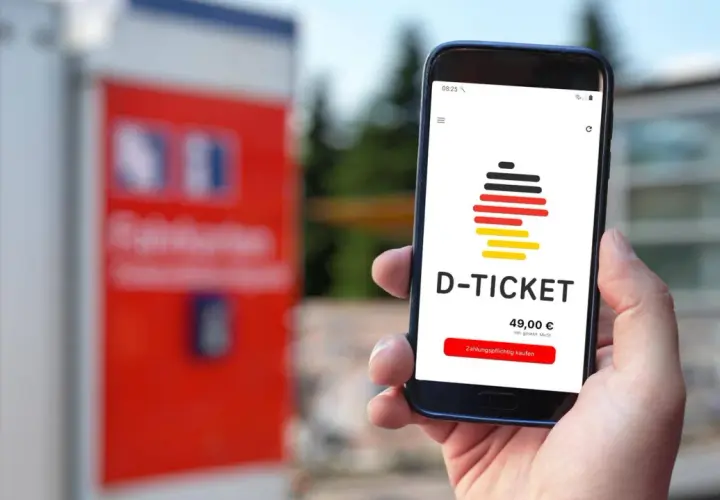 Hand hält Smartphone mit D-Ticket App. Preis 49,00 € wird angezeigt. Einfach das Deutschlandticket aktualisieren und losfahren.