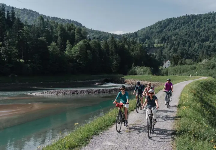 Eine Gruppe radelt entlang eines Flusses in den Bergen. Die komoot Fahrrad App hat sie sicher hierher geführt.