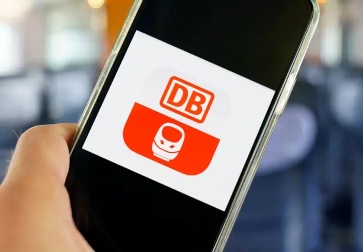 Hand hält Smartphone mit DB-App. Hier kann man unkompliziert ein DB Ticket stornieren.