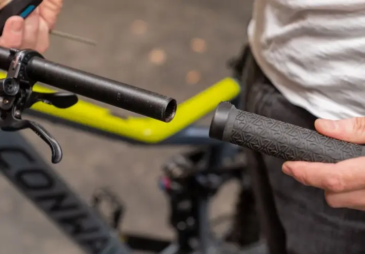 Person wechselt Lenkergriffe am Fahrrad. Ein neuer Griff wird auf den Lenker geschoben.