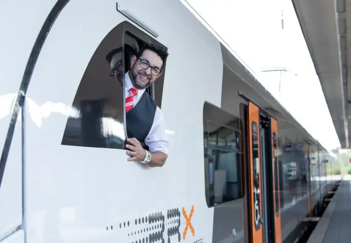 Ein freundlicher Lokführer winkt aus dem Fenster eines RRX Zuges.