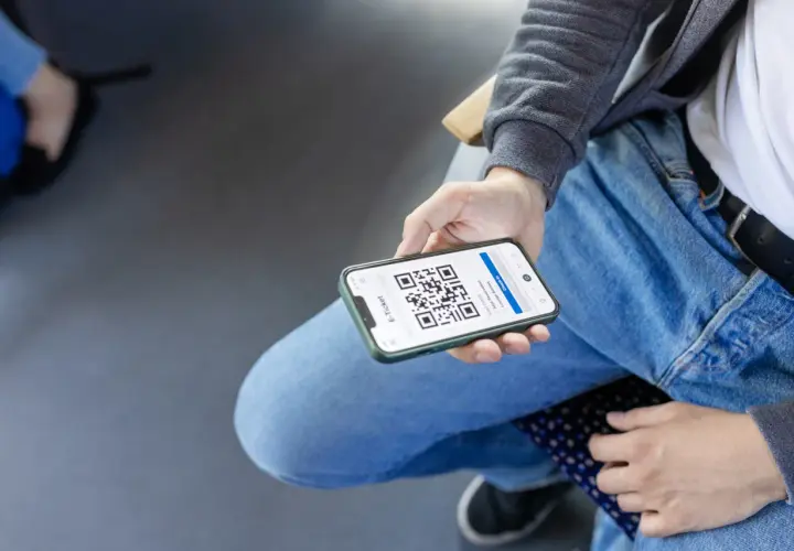 Person zeigt Smartphone mit QR-Code für Deutschlandticket-Kontrolle.
