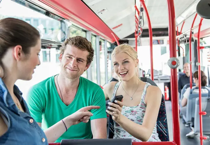 Drei Freunde unterhalten sich lachend im Bus. Sie fahren an Feiertagen NRW und genießen die gemeinsame Fahrt.