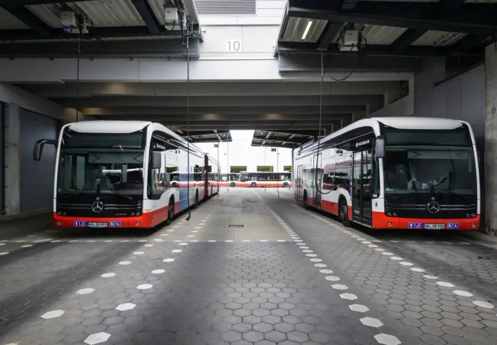 Zwei moderne Stadtbusse stehen unter einem Vordach. Man fragt sich, wie viel PS ein Bus hat, um diese Giganten zu bewegen.