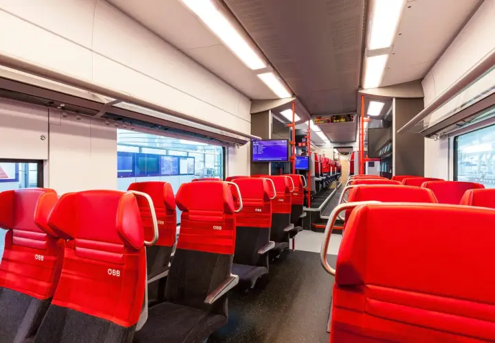 Rote Sitze im modernen Desiro ML Zug der ÖBB. Die Sitze sind mit dem ÖBB-Logo versehen und laden zu einer angenehmen Reise ein.