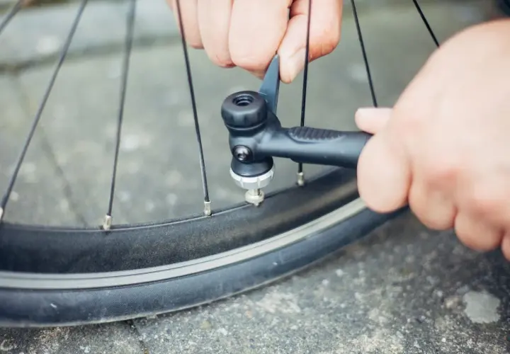 Hände pumpen mit einer Handpumpe Luft in ein Fahrradventil.