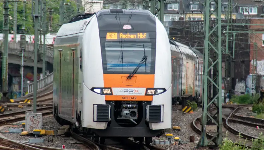 Ein moderner Zug der SPNV Linien NRW fährt auf Gleisen. Die Anzeige zeigt "RE1 Aachen Hbf".