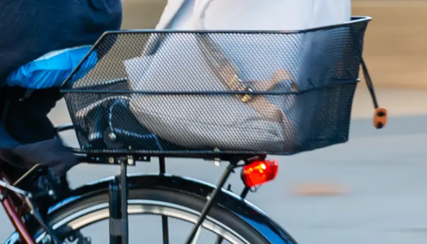 Anleitung: Fahrradkorb hinten befestigen. Ein schwarzer Drahtkorb mit Gepäck ist auf einem Fahrrad montiert.
