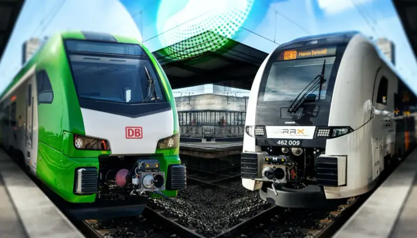 Zwei moderne Züge, ein grüner DB und ein weißer RRX, stehen nebeneinander am Bahnsteig.
